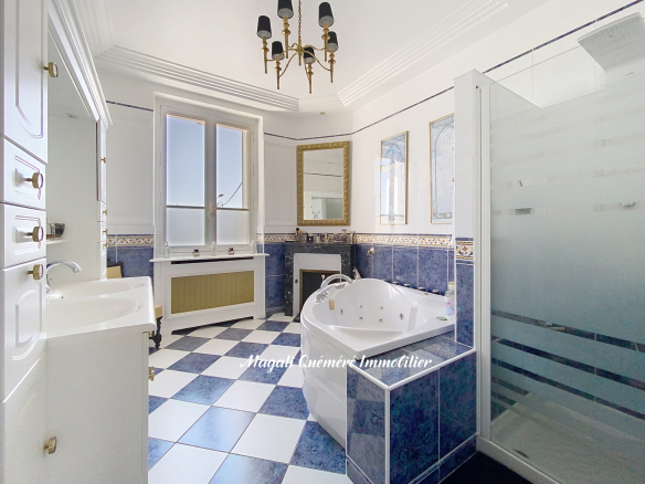 Elegant white-and-blue bathroom with a corner whirlpool tub, double sink, frosted glass shower, and large windowed wall.