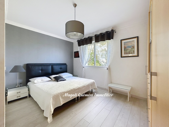 Modern bedroom with gray accent wall, black tufted headboard bed, white bedding, and two white nightstands with lamps.