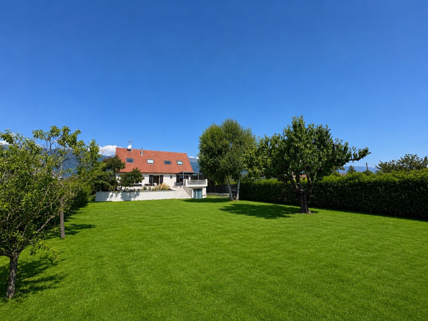 House in Saint-Genis-Pouilly House with a green garden in Saint-Genis-Pouilly under a blue sky.