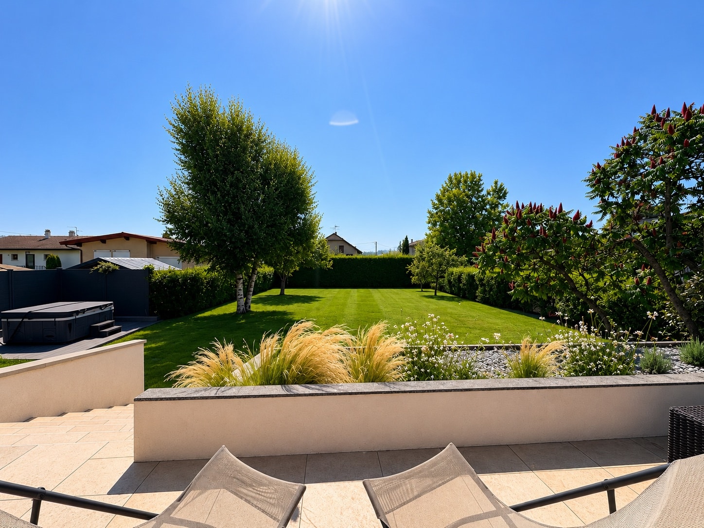 House garden in Saint-Genis-Pouilly View of a spacious and well-maintained garden with lawn and trees, sunny.