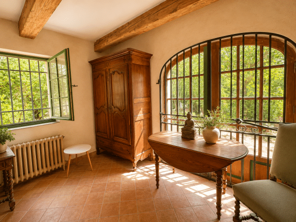 Intérieur d'un mas provençal avec fenêtres ouvertes et mobilier en bois à Aubagne.