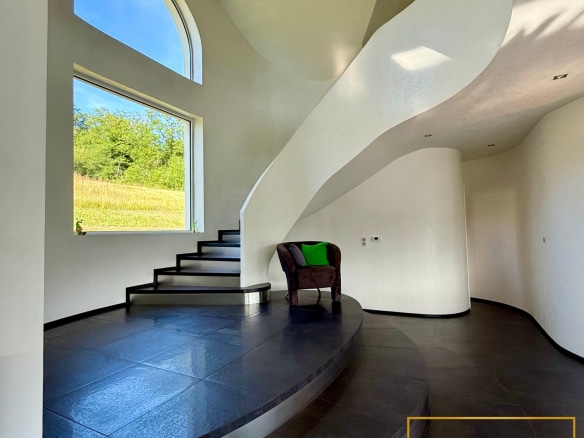 Intérieur d'une villa moderne avec un escalier en colimaçon et une grande fenêtre.