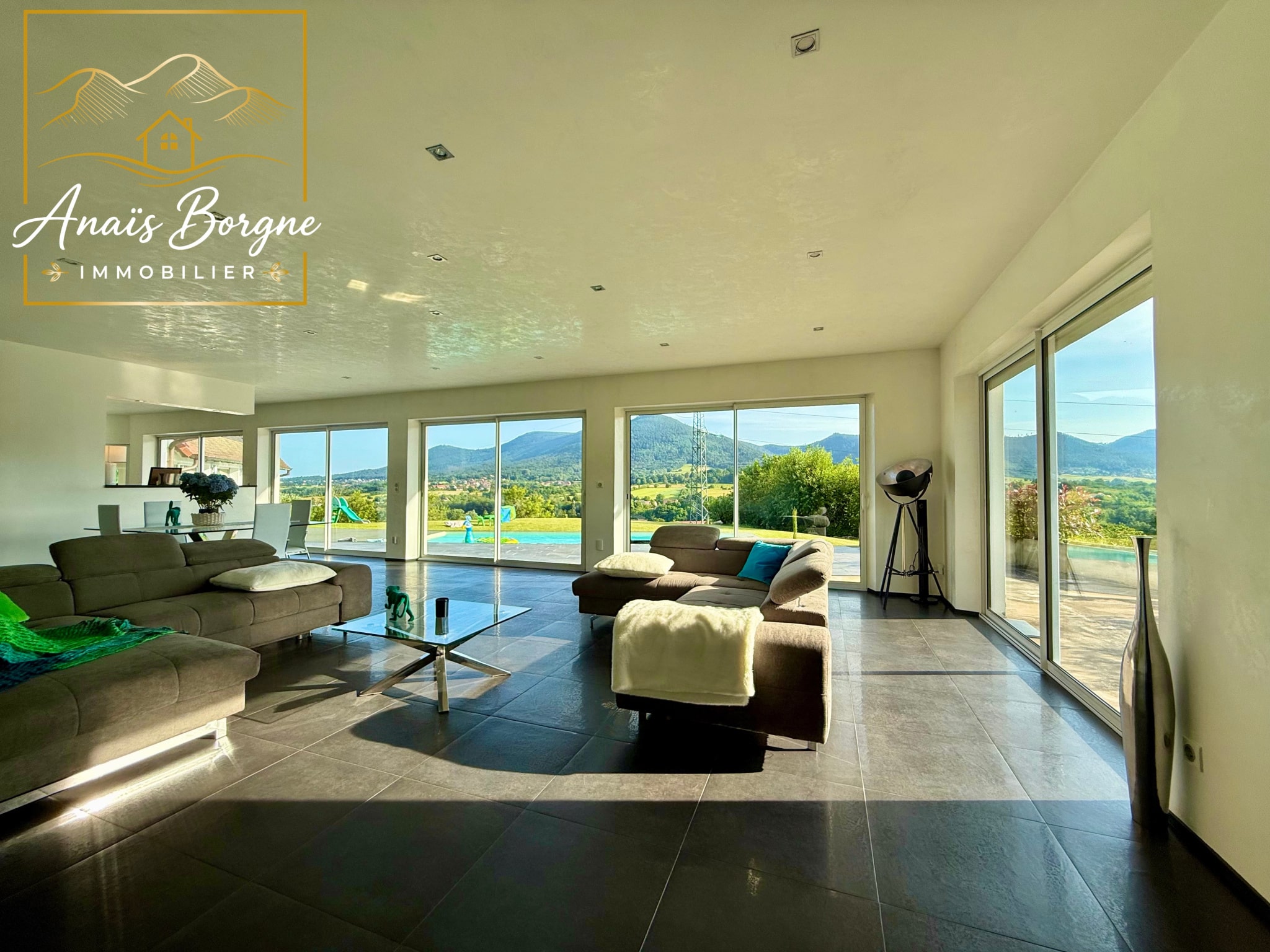 Intérieur d'une villa moderne avec vue panoramique sur la vallée, grandes baies vitrées.