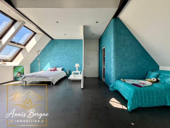 Chambre spacieuse avec murs turquoise et lit, vue sur la vallée depuis la villa à Villé.