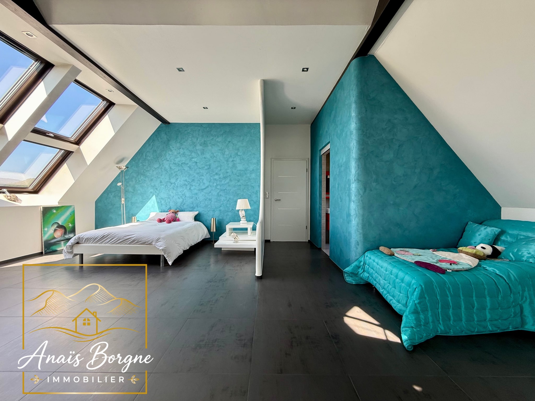 Chambre spacieuse avec murs turquoise et lit, vue sur la vallée depuis la villa à Villé.