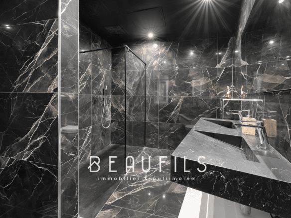 Salle de bain moderne avec carrelage noir marbré et vasque design.