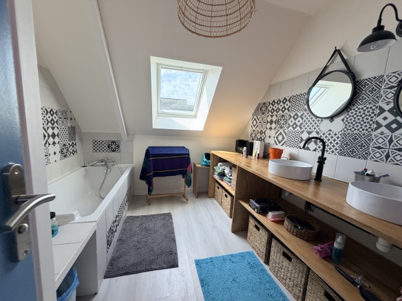 Salle de bain moderne avec baignoire, lavabos et rangement en bois.