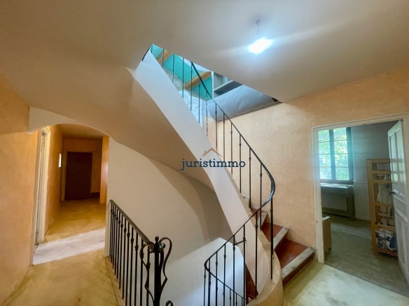 Escalier intérieur d'une propriété élégante avec murs clairs et balustrade en fer forgé.