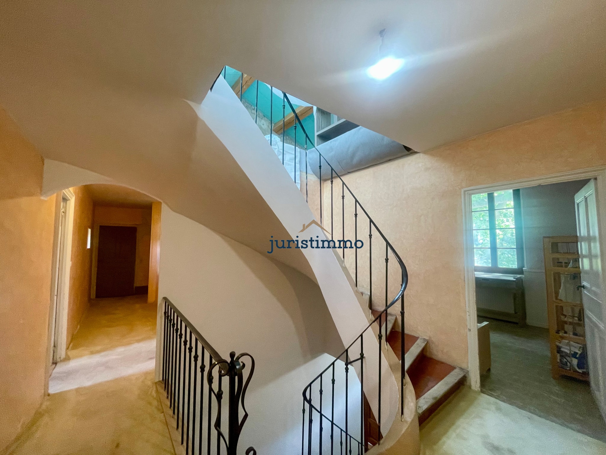 Escalier intérieur d'une propriété élégante avec murs clairs et balustrade en fer forgé.