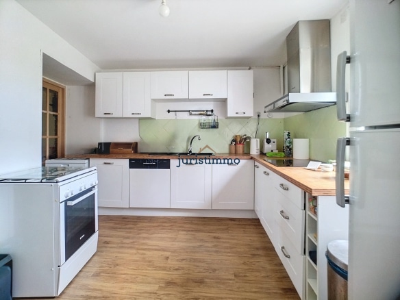 Cuisine moderne et lumineuse dans une propriété en Provence, avec meubles blancs et plan de travail en bois.