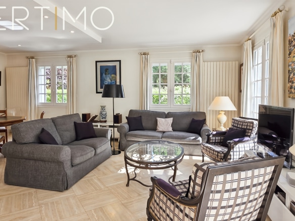 Interior of a bright living room with elegant furniture and windows overlooking the garden.