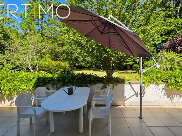 Terrace with parasol and garden furniture in a green park in La Norville.