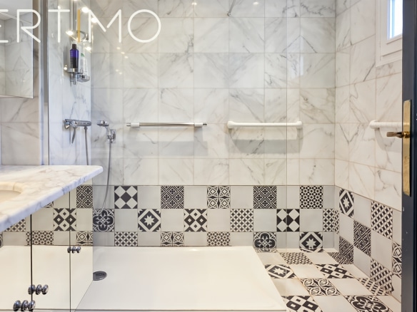 Modern bathroom with black and white tiles, walk-in shower and marble sink.