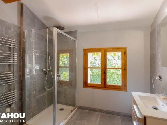 Salle de bain moderne avec douche à l'italienne et fenêtre donnant sur l'extérieur.