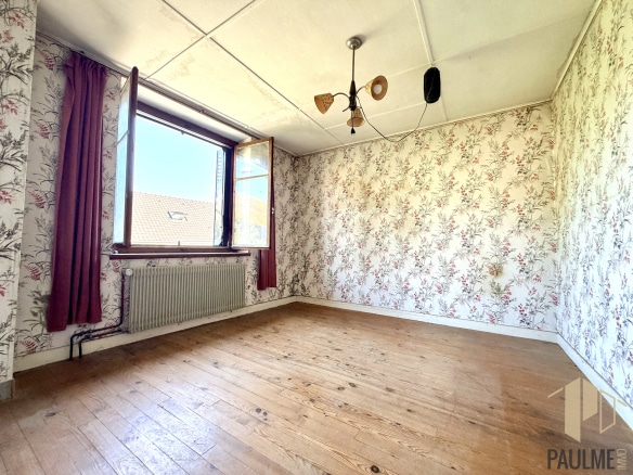 Intérieur d'une pièce vide avec papier peint fleuri et fenêtre à Ornex.