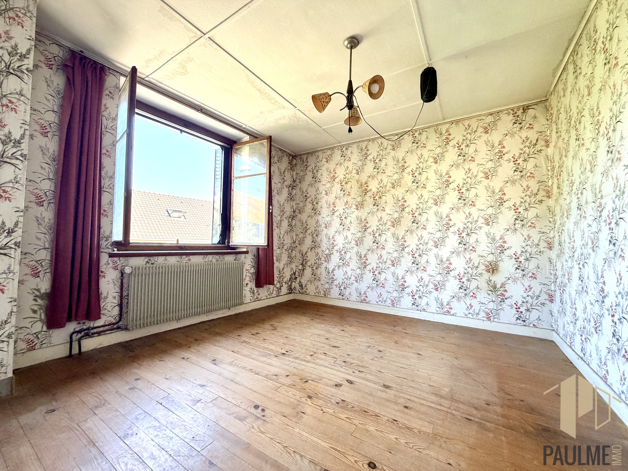 Intérieur d'une pièce vide avec papier peint fleuri et fenêtre à Ornex.