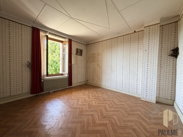 Intérieur d'une grange à rénover avec un sol en parquet et des murs tapissés à Ornex.