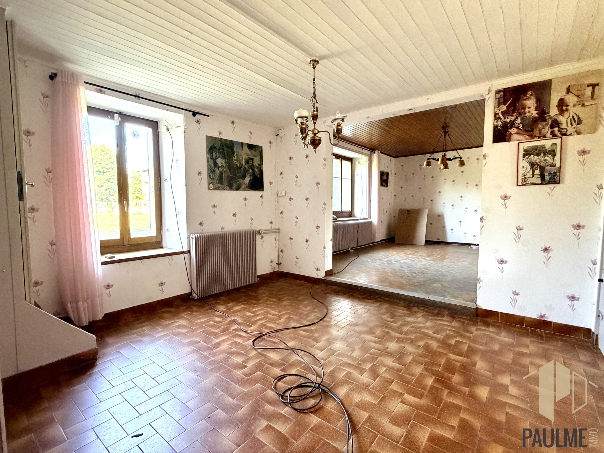 Intérieur d'une grange à rénover avec des murs fleuris et un sol en carrelage à Ornex.