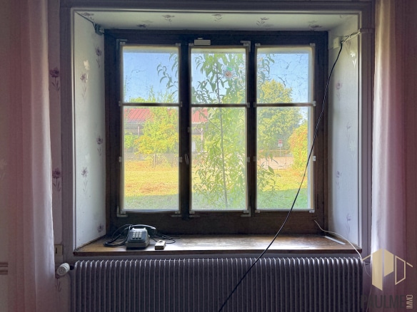 Fenêtre en bois avec vue sur un jardin, à l'intérieur d'une grange à Ornex.