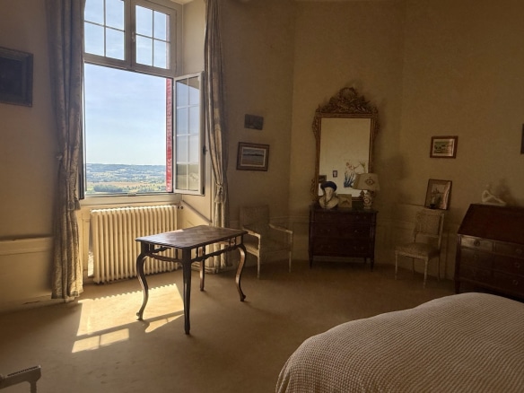 Intérieur d'une chambre avec vue sur la vallée, mobilier ancien et lumière naturelle