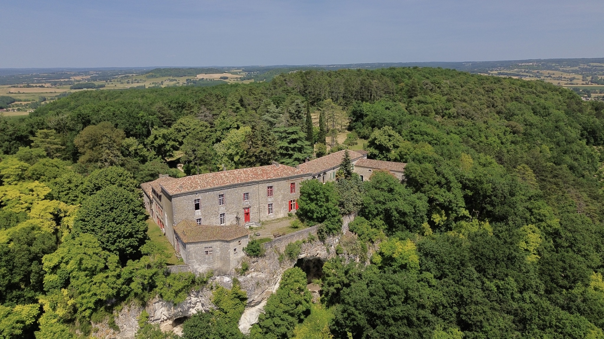 Vue aérienne d'un château en pierre entouré de verdure, situé près de Penne-d'Agenais.