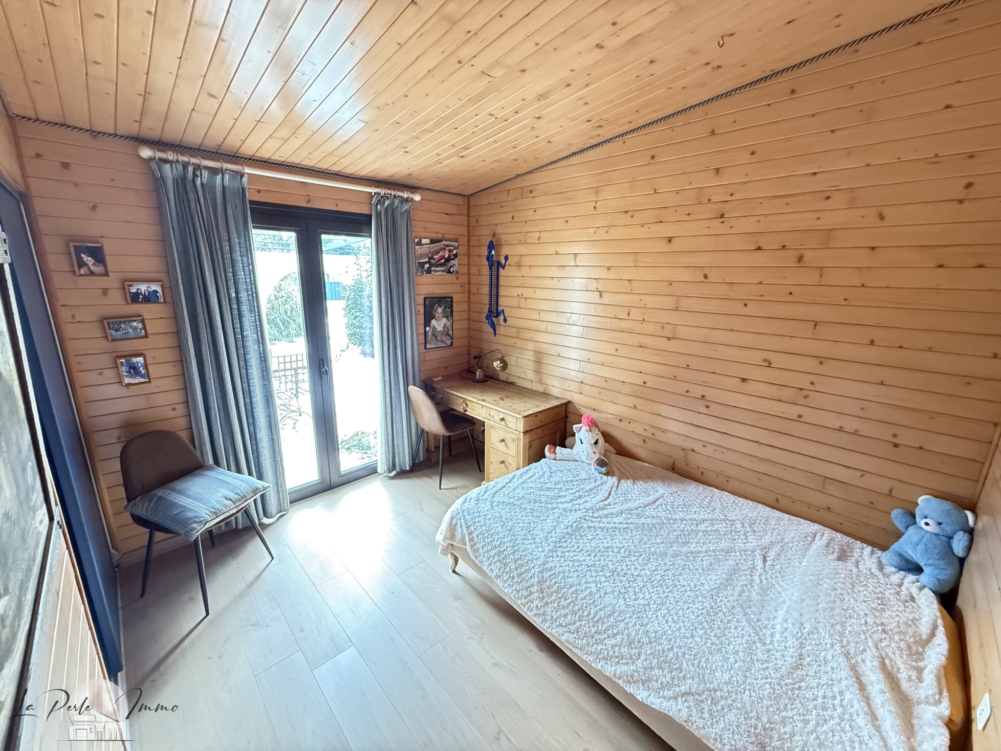 Chambre d'une villa en bois avec un lit simple, un bureau et une fenêtre donnant sur l'extérieur.