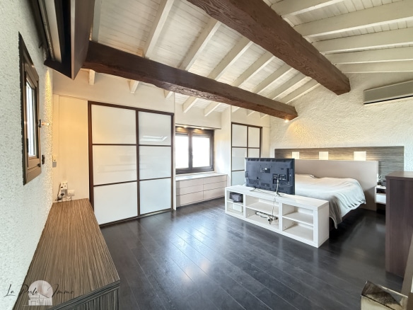 Chambre spacieuse avec plafond en bois et télévision dans une villa à Perpignan.
