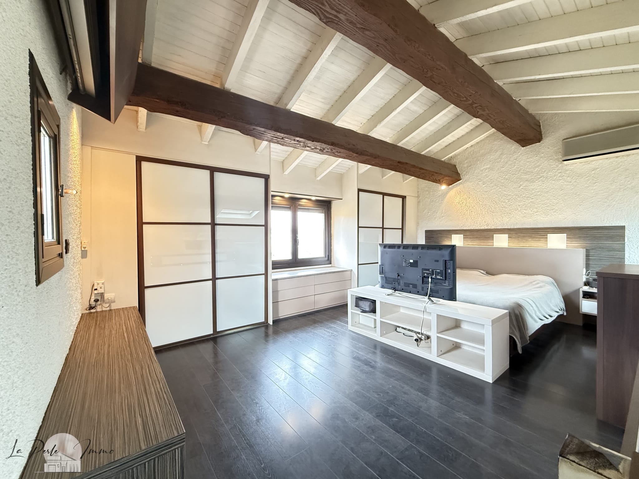 Chambre spacieuse avec plafond en bois et télévision dans une villa à Perpignan.