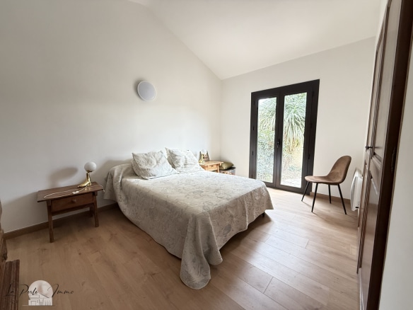 Chambre d'une villa de charme avec lit double, fenêtres donnant sur un jardin.
