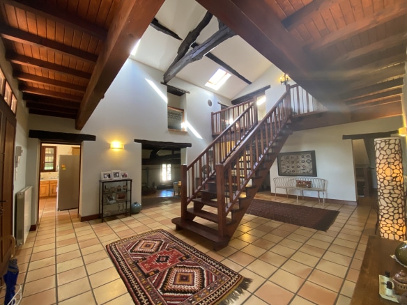 Interior of a country house in Moissac with a wooden staircase and stone walls.