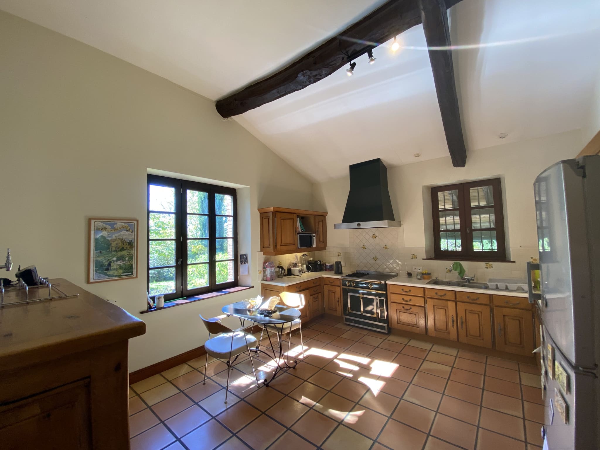 Spacious and bright kitchen in a country house in Moissac, with windows and wooden furniture.