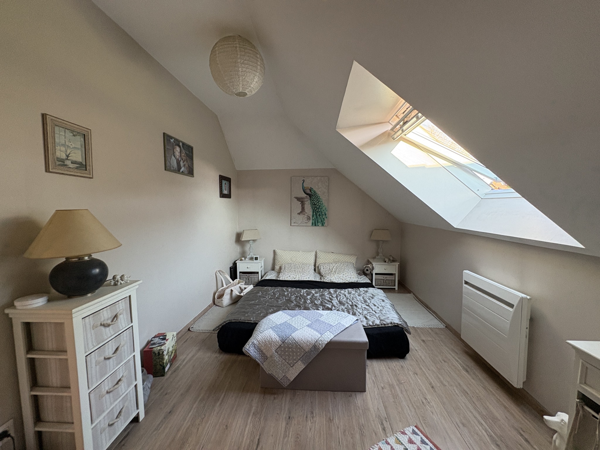 Chambre spacieuse avec lit, meubles clairs et lumière naturelle