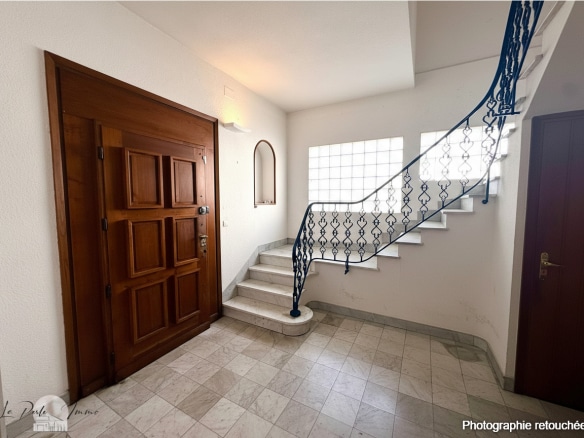 Intérieur d'une maison de maître avec un escalier et une porte en bois à Perpignan.