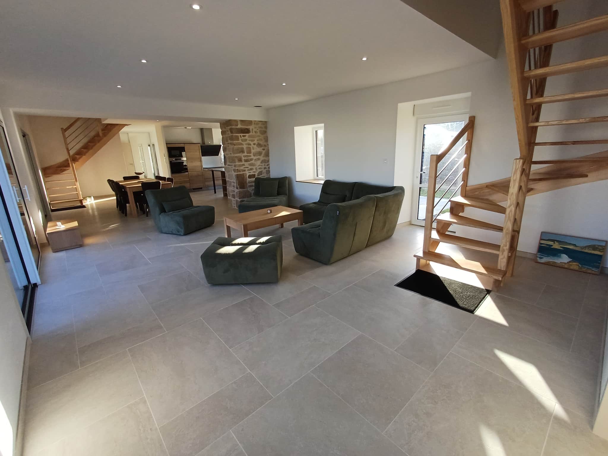 Interior of a Breton stone house in Plougasnou, with a spacious living room and a wooden staircase.
