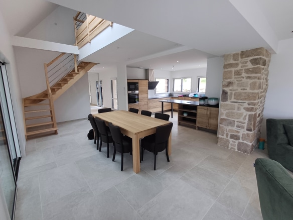 Interior of a renovated Breton stone house, with living room, dining room and open kitchen.