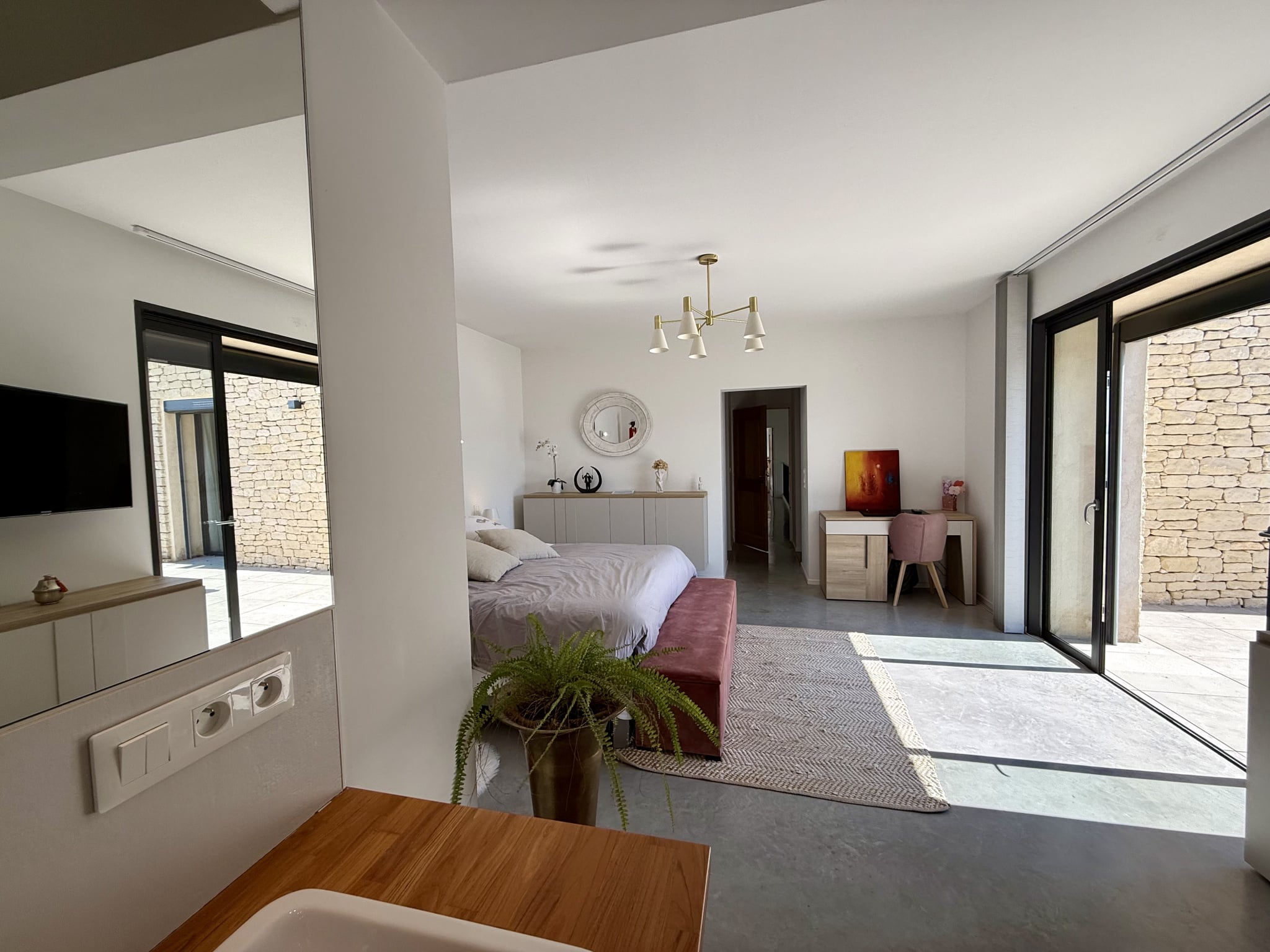 Intérieur d’une maison d’architecte à Gordes Intérieur d'une maison contemporaine avec un lit, un bureau et de grandes baies vitrées.