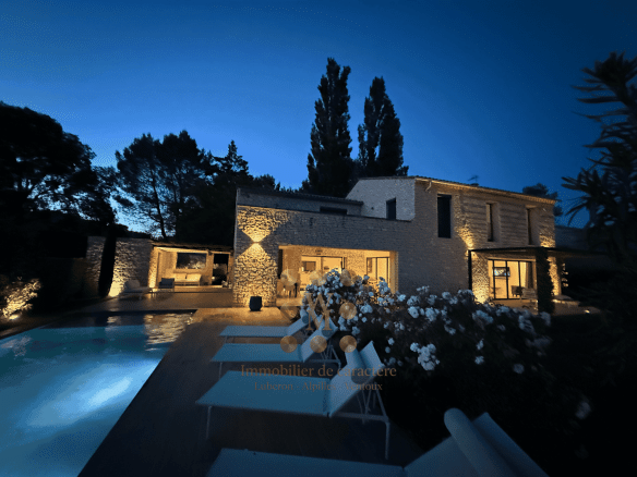 Maison contemporaine avec piscine et jardin à Gordes, éclairée la nuit.