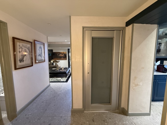 Intérieur d'une maison de maître avec un ascenseur et des œuvres d'art aux murs.