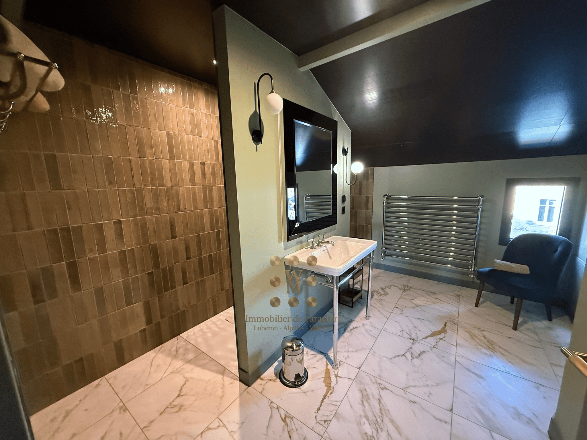 Salle de bain moderne avec carrelage en marbre et lavabo sur meuble, lumière douce.