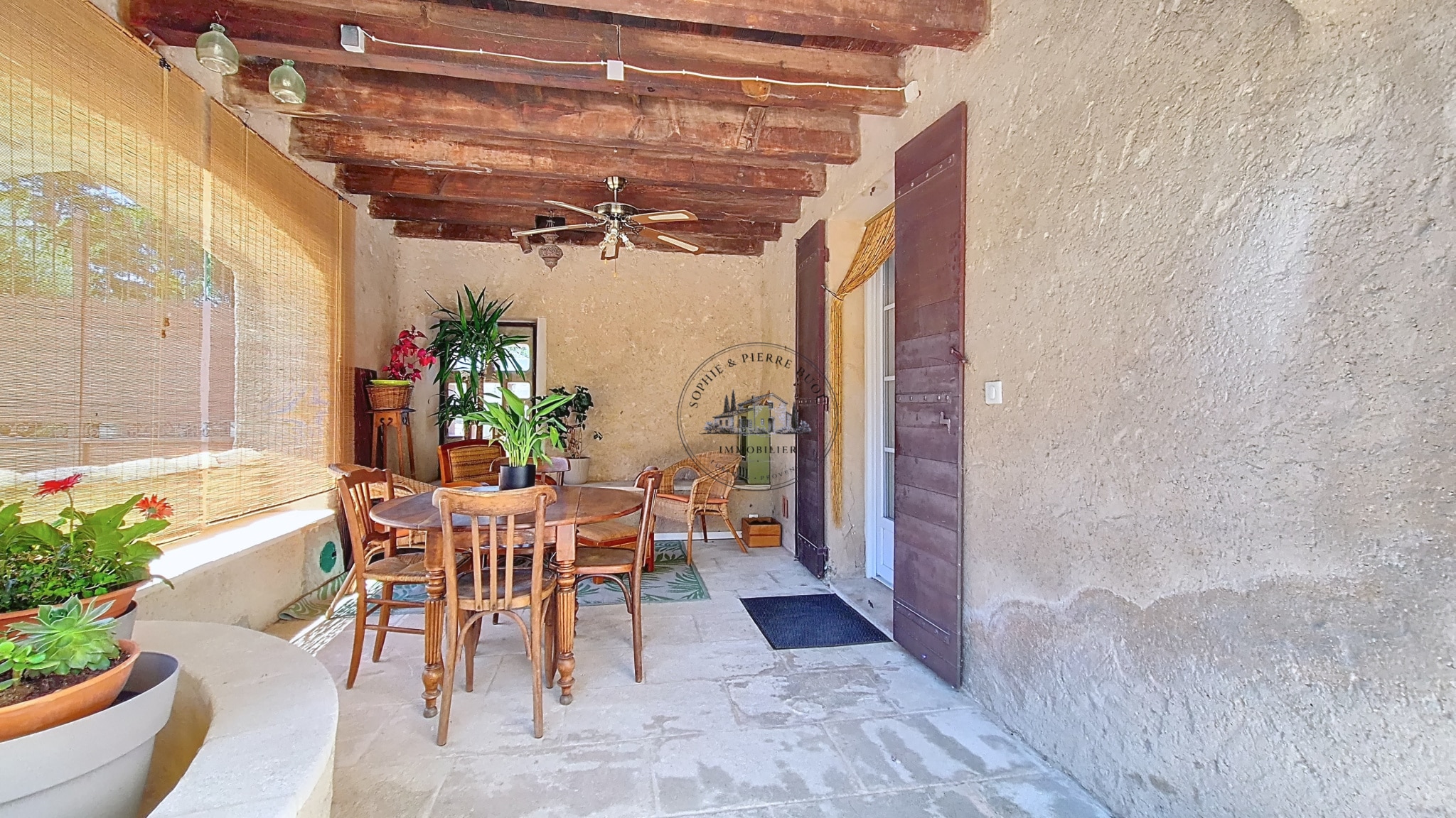 Terrace of an 18th century building with wooden furniture and plants, Cheval-Blanc.