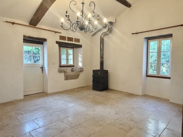 Interior of a stone property with beamed ceiling and fireplace, located in Touffailles.