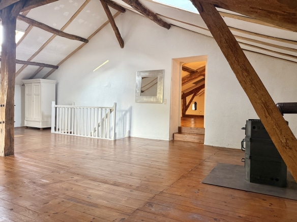 Interior of a stone house with exposed beams and wooden parquet flooring.