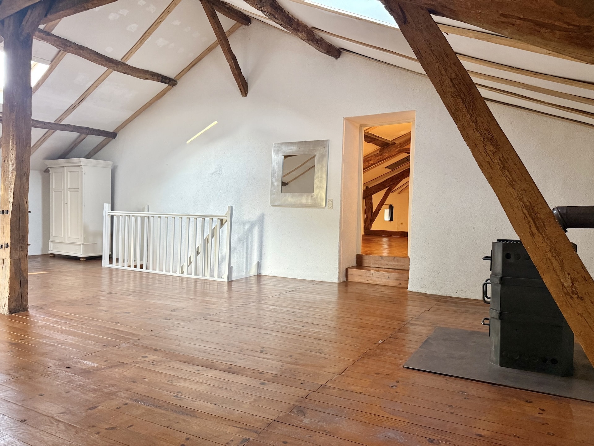 Interior of a stone house with exposed beams and wooden parquet flooring.