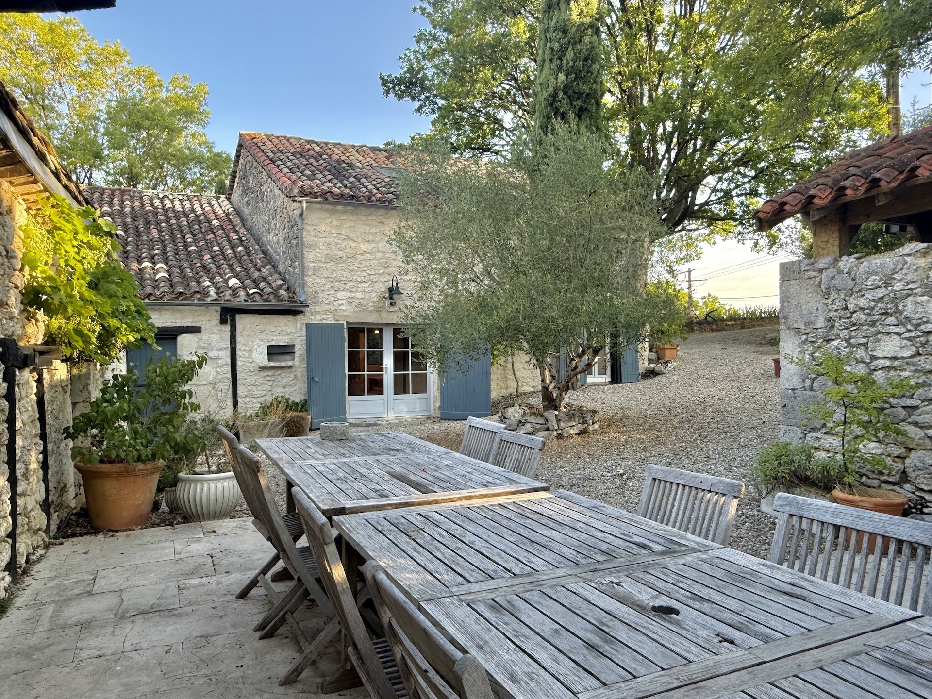 Stone ensemble with swimming pool and wooden table in a courtyard, in Touffailles.