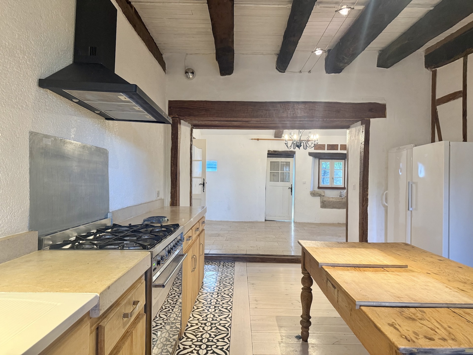 Interior of a kitchen with a wooden worktop and modern appliances, overlooking a living space.