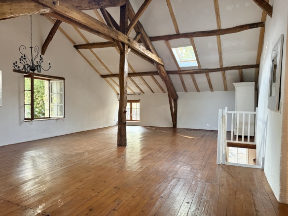 Interior of a stone property with exposed beams and wooden floor, bright and spacious.