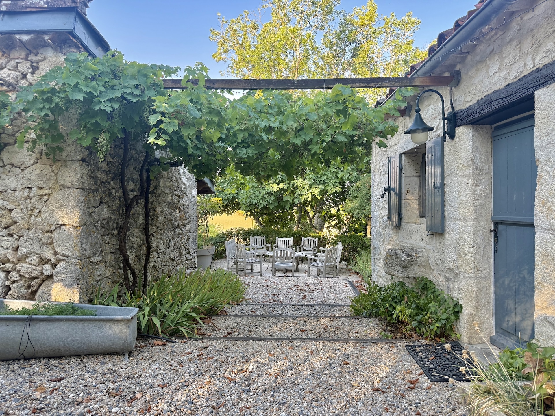 View of a stone complex with a courtyard and chairs, surrounded by greenery in Touffailles.