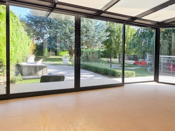 Bright interior of a house with large bay windows overlooking a wooded garden.