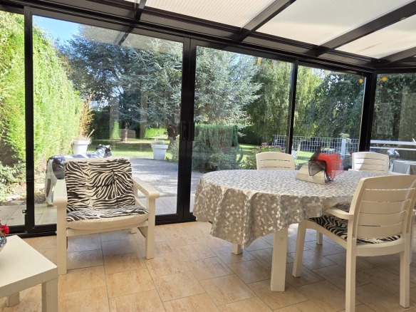 Bright veranda with furniture, overlooking a wooded garden.