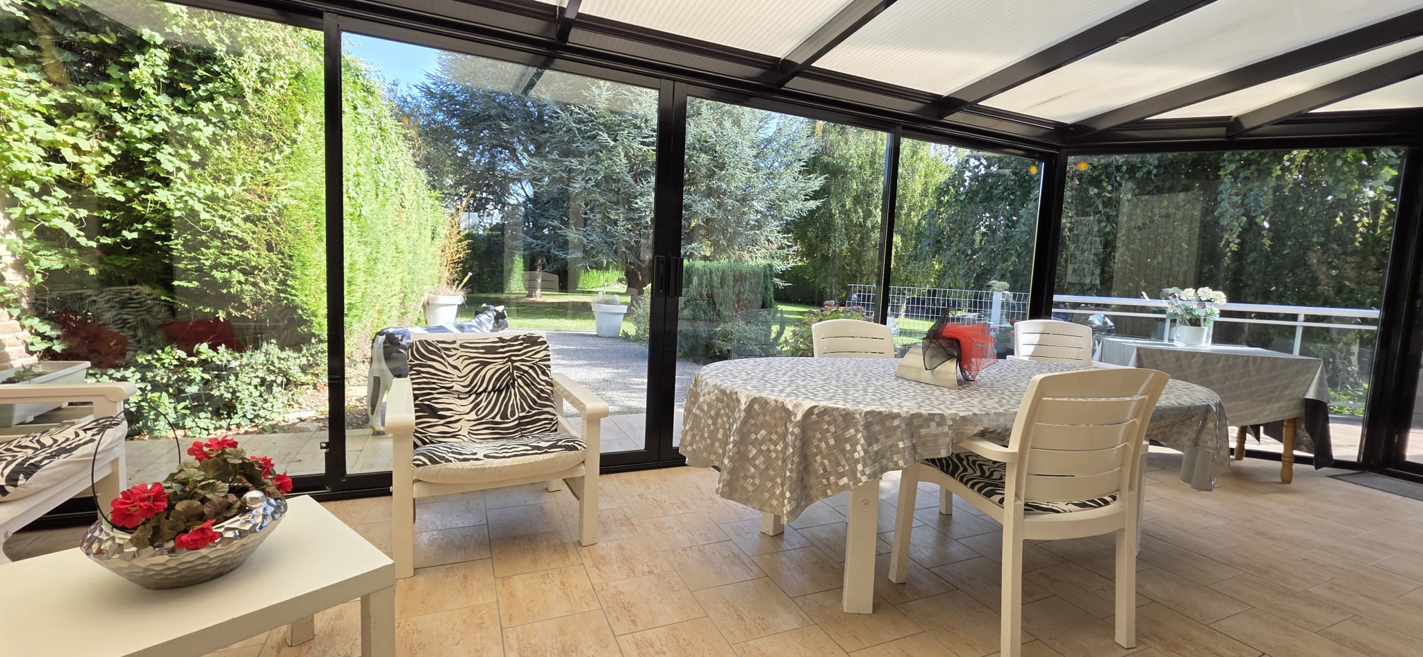 Veranda of the house in Bauvin Bright veranda with furniture, overlooking a wooded garden.